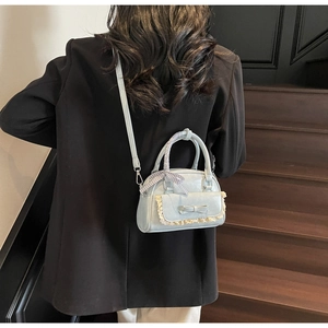 Detail van lichtblauwe tas met strik, kantdetail en zwart-wit geblokt lint