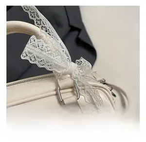 Detailed close-up of cream leather bowling bag with silver hardware and lace bow decoration