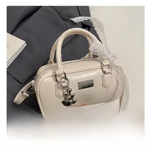 Close-up of cream leather bowling bag with heart bear pendant and white lace bow