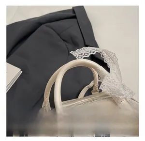 Detail view of smooth cream Boston bag handles with elegant white lace ribbon decoration