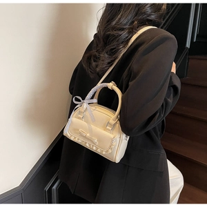 Detail van beige handtas met strik en kant op een model dat op de trap loopt