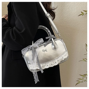 Detail of silver metallic Boston bag with black bow and lace trim on a model