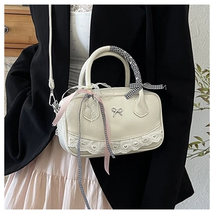 Close-up of beige leather bowling bag with bow buckle, lace trim and ribbon handle