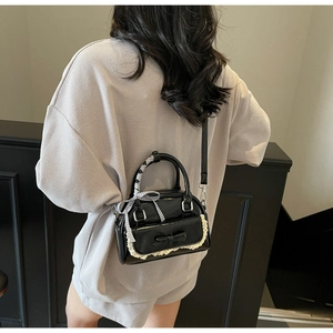 Detail of black bow handbag with lace edges and checkered ribbon handle shown on a model