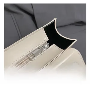 Detailed close-up of cream leather handbag showing silver metal zipper and precise stitching