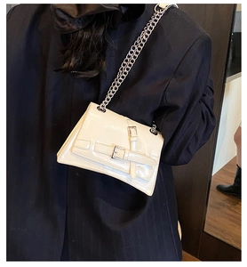 Détail du sac asymétrique crème avec boucles argentées et bandoulière chaîne sur modèle
