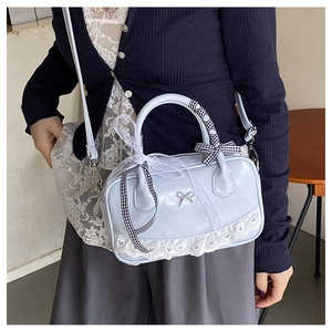 Detail of light blue glossy leather bag with white lace heart and silver bow charm