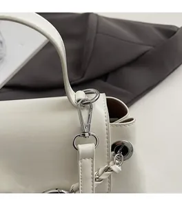 Close-up of premium silver hardware and fine leather texture on white crossbody bag