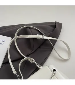 Detail of adjustable white leather strap and silver metal buckle on a small square bag