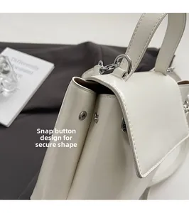 Detail of silver snap button and structure on a creamy white handbag with fine leather texture