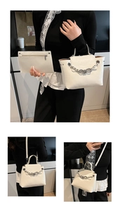 Close-up of white glossy patent leather handbag set with silver chain and bow detail