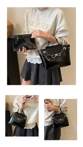 Detail view of the black tote bag with silver chain and bow knot on smooth leather surface