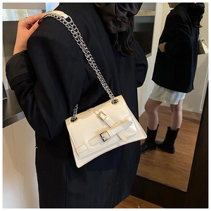 Detail of cream chain shoulder bag with metallic buckles on textured faux leather
