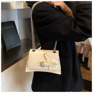 Detailed view of a cream crossbody bag with silver chain straps and buckle worn by a model