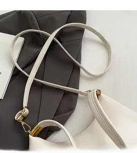 Detailansicht des cremefarbenen Lederriemens und der Goldbeschläge dieser eleganten Tasche