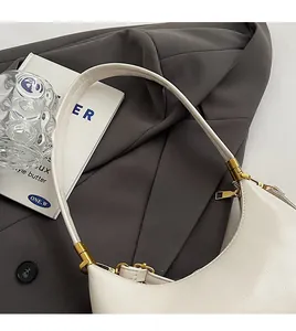Detailansicht der cremefarbenen Halbmondtasche mit verstärktem Griff und Goldbeschlägen