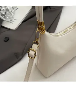 Details der cremefarbenen Ledertasche mit goldenem Karabiner und verstellbarem Riemen