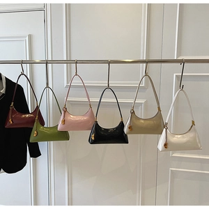 Sechs bunte Hobo-Taschen mit Metallanhängern an einer Kleiderstange in Reihe
