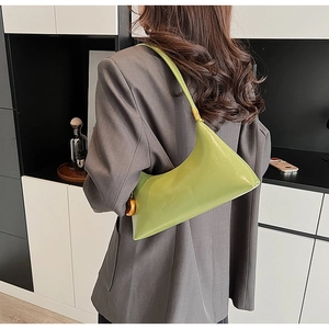 Detailansicht einer glänzenden hellgrünen Sichel-Schultertasche mit goldenen Beschlägen