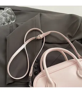 Détail du sac à main en cuir rose avec bandoulière réglable et texture mate