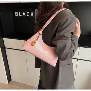 Detail der rosa Hobo-Schultertasche mit goldener Kette und metallischem Bohnen-Anhänger