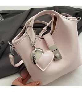 Detail of pink leather bucket bag with silver heart charm on a gray blazer backdrop