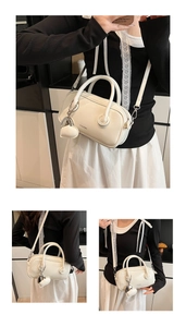 Détails d'un sac Boston blanc avec pendentif en forme de cœur et bandoulière amovible