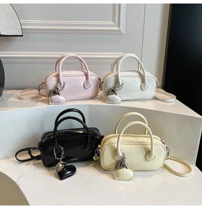 Détail de quatre sacs à main carrés en rose, blanc, noir et beige avec breloques coeur