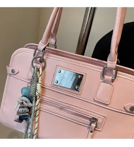 Detail of pink PU tote bag featuring silver hardware and a cute cartoon dog pendant