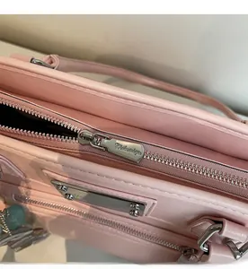 Close-up of high-quality silver metal zipper and smooth leather texture on pink handbag