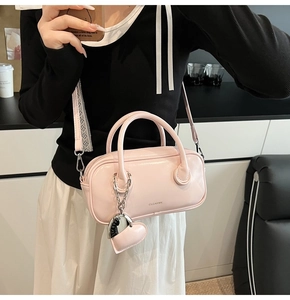 Close-up of light pink leather mini Boston bag with heart charm and Clear K logo