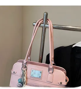 Pink faux leather tote bag detail with silver logo plaque and cute doll charm