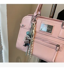 Detail of pink PU leather handbag showing brand metal plate and cute puppy charm accessory