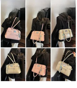 Detail view of pink and beige PU leather shoulder bags with tassel charms and metal logo