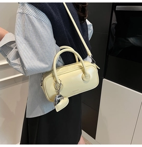 Détail d'un sac oreiller en cuir crème avec breloque cœur et logo CLEAR K