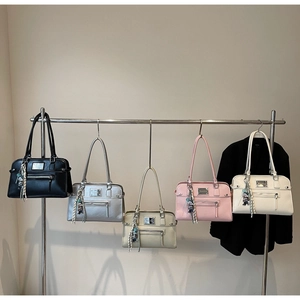 Row of leather Boston handbags in five colors with metal hardware and tassel detail