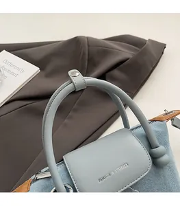 Detail of denim and leather bag featuring Pantor & Stories logo and metal zipper