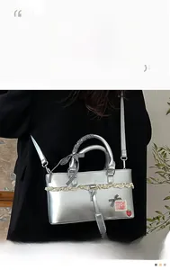 Detail of silver crossbody bag with checkered bow handle and white lace trim