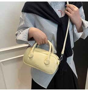 Détail du sac Boston jaune clair avec doubles poignées et logo Clear K en métal argenté