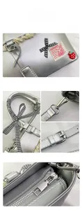Detail of silver metallic bag featuring a checkered bow, lace trim, and strawberry charm