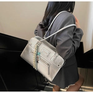Detail of silver metallic shoulder bag with tassel and plush bear charm on model