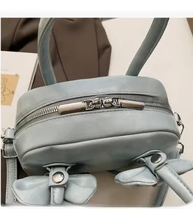 Détail de la fermeture éclair argentée et du nœud sur le sac à main en cuir bleu clair