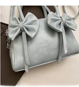 Détail du sac à main bleu clair avec nœuds, texture en cuir souple et logo embossé