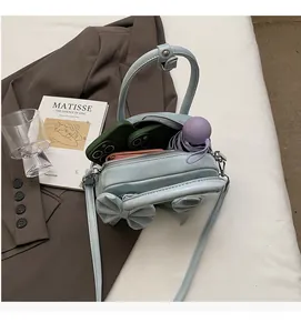 Intérieur spacieux d'un sac à main bleu clair avec nœud contenant téléphone et portefeuille