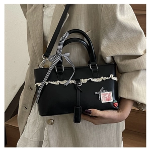 Detail of black crossbody bag with white lace, checkered bow, and cute rabbit patch