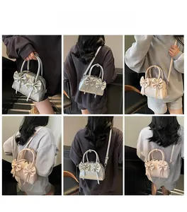 Vues détaillées d'un sac Boston à nœud en argent et beige, porté en bandoulière et à la main