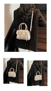 Détail du sac Boston crème avec décoration nœud et élégant gaufrage de lettres