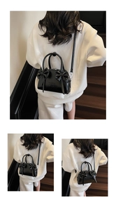 Gros plan du sac Boston en cuir verni noir brillant avec nœuds papillon chic