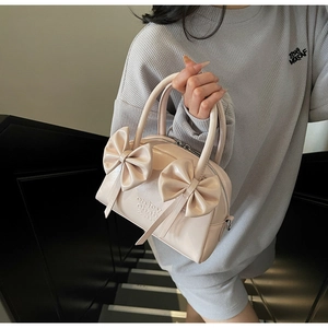 Détail du sac à main beige à nœuds avec texture embossée et finitions métalliques élégantes