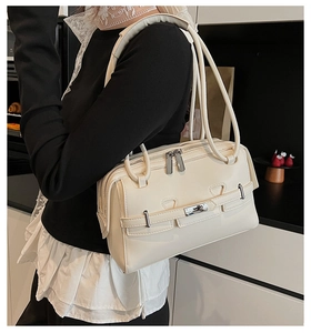 Detailed close-up of cream leather shoulder bag with silver buckles and multi-strap handle